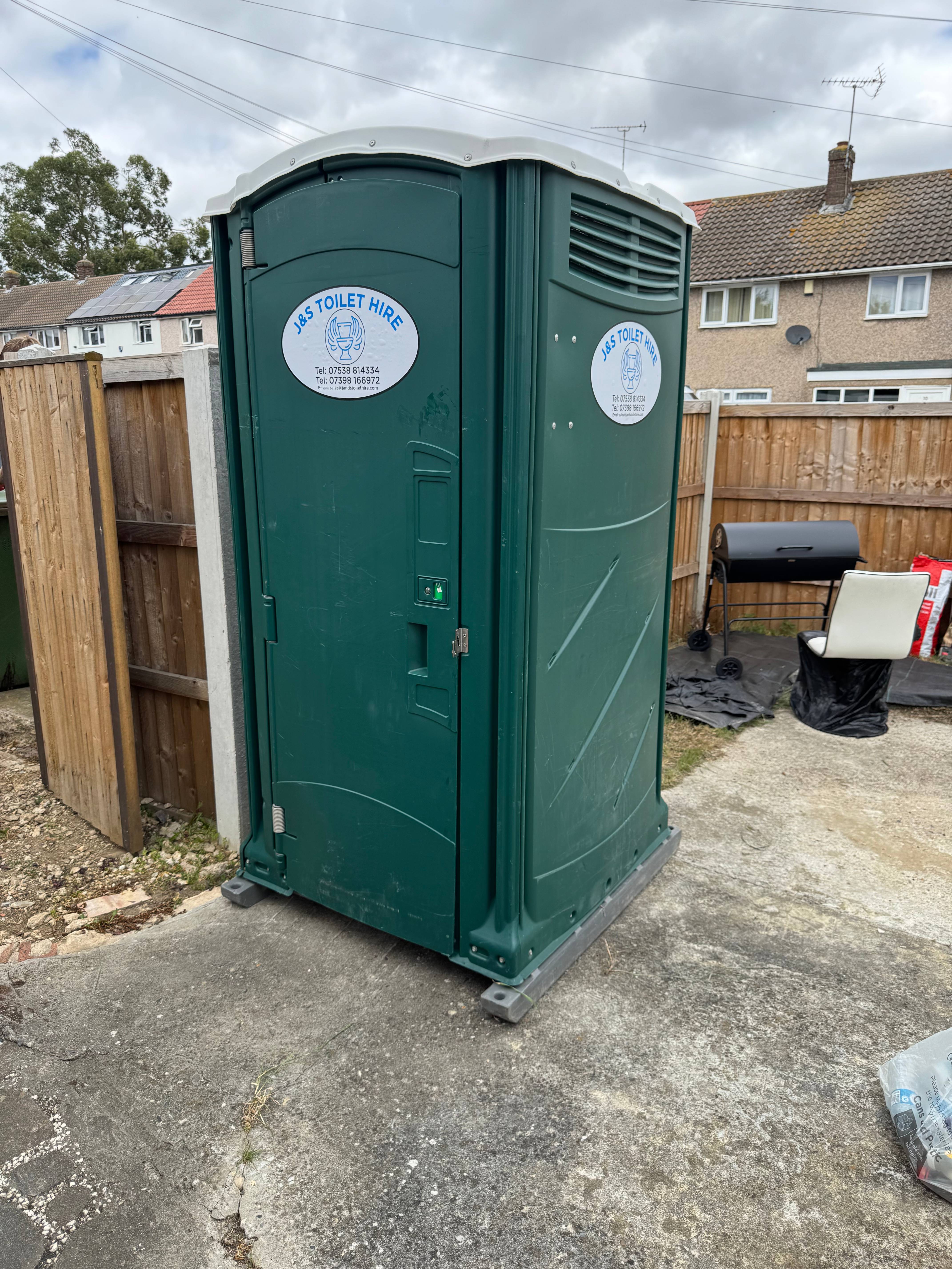 Single green J&S Toilet Hire portable toilet in residential backyard setting